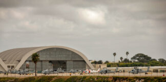 Hangar with military helicopters near a beach.