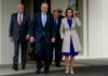 Group of officials walk outside a building entrance.