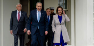 Group of officials walk outside a building entrance.