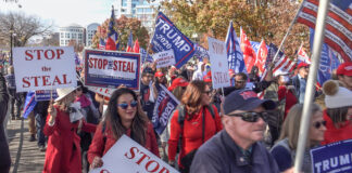 Protesters holding signs and flags at a rally