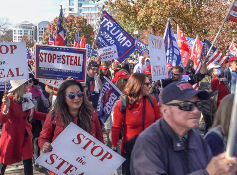 Protesters holding signs and flags at a rally