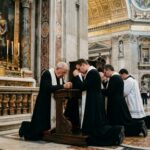 Clergy members kneeling in prayer inside a grand cathedral