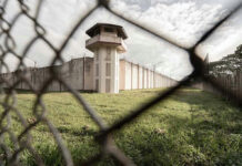 View of prison watchtower through chain-link fence.