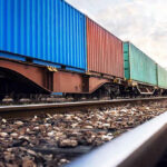 Train with colorful cargo containers on railway track.