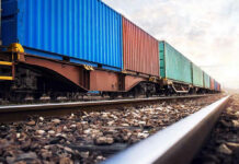 Train with colorful cargo containers on railway track.