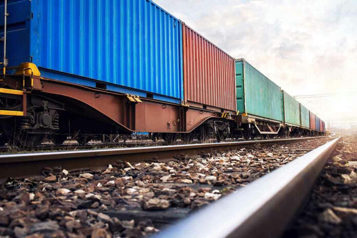 Train with colorful cargo containers on railway track.