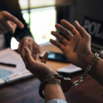 Handcuffed person is questioned by a police officer.