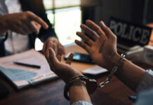 Ex-CIA Official BUSTED: $40 Million Gold Stash… Handcuffed person is questioned by a police officer.
