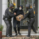 Police arresting person holding a box.
