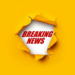 Breaking News text on yellow torn paper background.