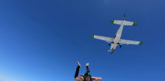 Skydiver jumping from airplane in clear blue sky