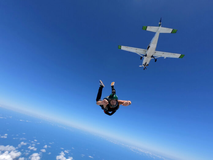 Skydiver jumping from airplane in clear blue sky