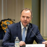 A man in a suit speaking into a microphone.