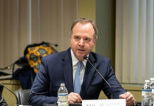 A man in a suit speaking into a microphone.