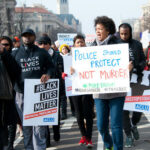 Protesters holding signs, including Police Should Protect Not Murder.