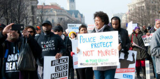 Protesters holding signs, including Police Should Protect Not Murder.