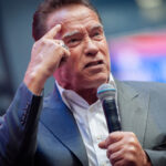 man in suit speaking into a microphone on stage