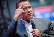 man in suit speaking into a microphone on stage