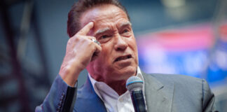 man in suit speaking into a microphone on stage