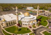 Aerial view of a mosque with golden domes and minarets surrounded by greenery