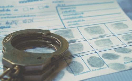 Handcuffs resting on a fingerprint card with inked fingerprints