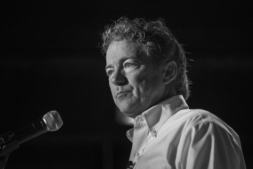 A man with curly hair speaking into a microphone in black and white
