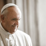 Pope Francis smiling in a white robe and zucchetto