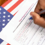 Person filling out voter registration form, American flag background.