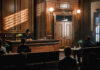 Judge presiding over courtroom with people seated inside.