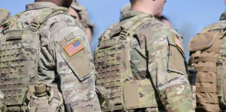 Soldiers in camouflage uniforms with American flags on sleeves.