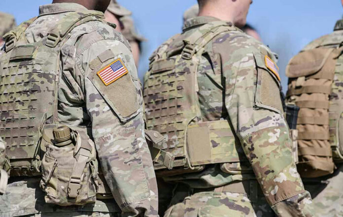 Soldiers in camouflage uniforms with American flags on sleeves.