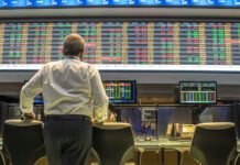 Inflation Alarm Blasts — Guess What Spiked Person viewing stock market data on multiple screens.