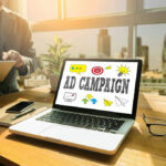 Laptop displaying Ad Campaign on desk in bright office.