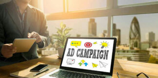 Laptop displaying Ad Campaign on desk in bright office.