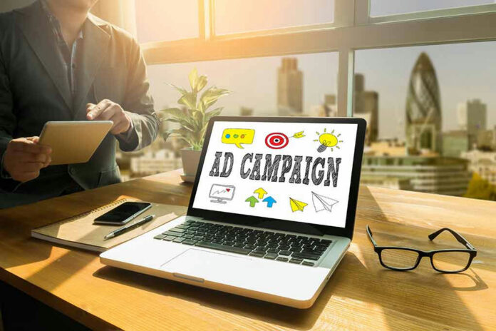 Laptop displaying Ad Campaign on desk in bright office.
