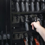 Hand reaching into a gun safe to pick up a handgun