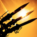 New Super-Missile Targets China’s Edge Silhouetted missiles on a launcher against a bright sunset sky