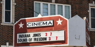 Cinema marquee on a brick building displaying current movie titles and showtimes
