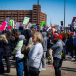 Large crowd of demonstrators holding signs at a protest