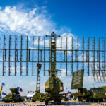 Military radar system displayed at an outdoor exhibition under a blue sky