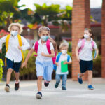 Children wearing masks running outside a school