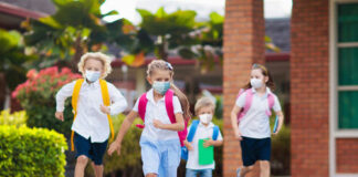 Children wearing masks running outside a school