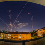 Ceasefire Teeters After Night Strikes Night sky with missile defense system intercepting rockets above city.