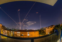 Ceasefire Teeters After Night Strikes Night sky with missile defense system intercepting rockets above city.