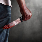 Congresswoman Minimizes Murder Knife A man holding a bloody knife behind his back in a dark setting