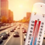 Thermometer displaying high temperature with a busy road in the background