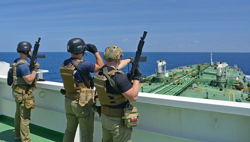 shutterstock_386613931 Armed security team on a ship deck overlooking a large tanker at sea