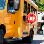 School bus with extended stop sign near students on sidewalk