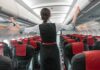 Flight attendant checks overhead bins in empty airplane cabin