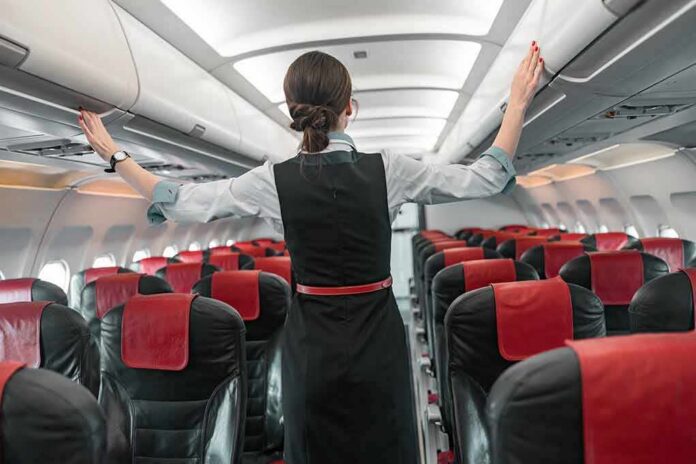 Flight attendant checks overhead bins in empty airplane cabin
